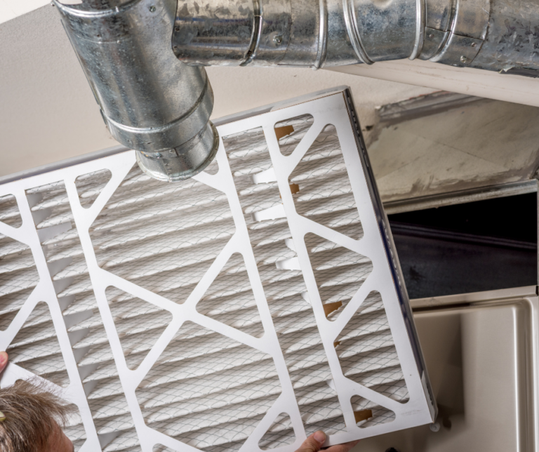 Personne remplaçant un filtre d’échangeur d’air dans un système de ventilation résidentiel